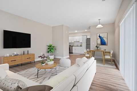 A living room with a white couch, a coffee table, a television, and a cabinet with a plant on top.