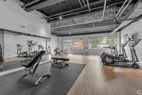 A gym with a variety of exercise equipment including treadmills, stationary bikes, and rowing machines.