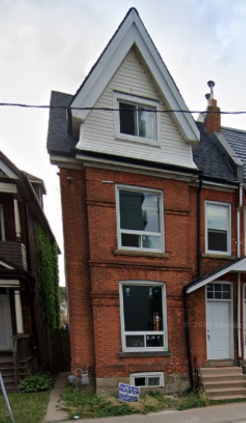 A red brick house with a white door and a window with a white frame.
