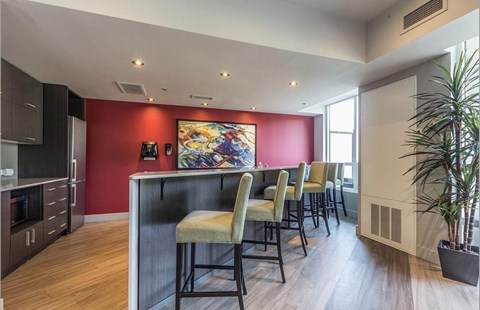 A kitchen with a red wall and a painting on it.