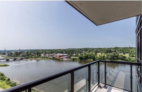A balcony overlooks a river with a bridge in the distance.