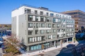 A modern multi-story building with a flat roof and large windows.