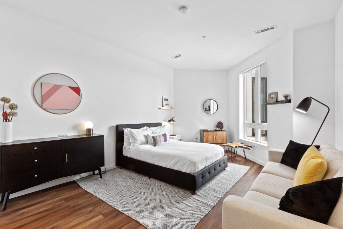 A modern bedroom with a large bed and a white couch.