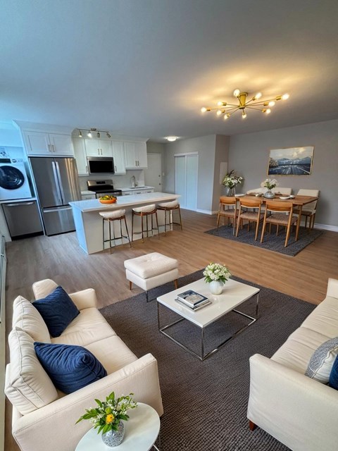 A modern living room with a kitchen in the background.