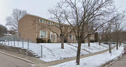 A brown house with a tree in front of it.