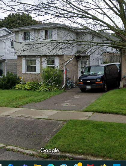 A white house with a black van parked in front.
