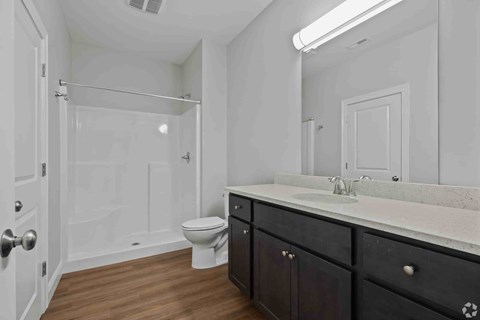A white bathroom with a toilet, sink, and shower.
