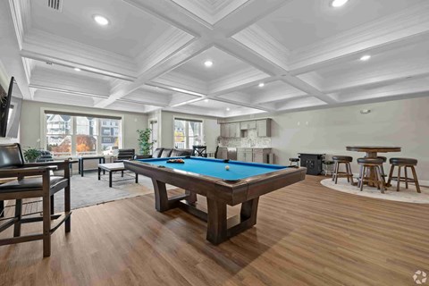 A room with a pool table and bar stools.