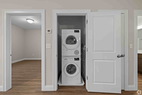 A white door is open to a room with a washer and dryer in it.