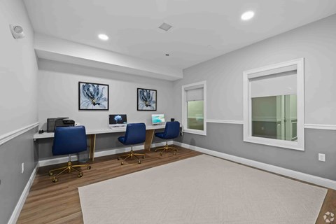 A room with a desk, chairs, and pictures on the wall.