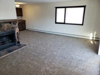 A living room with a fireplace and a grey carpet.