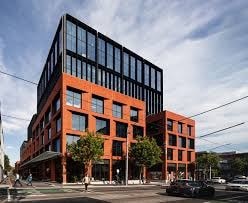 A modern red building with large windows and a black car parked in front.