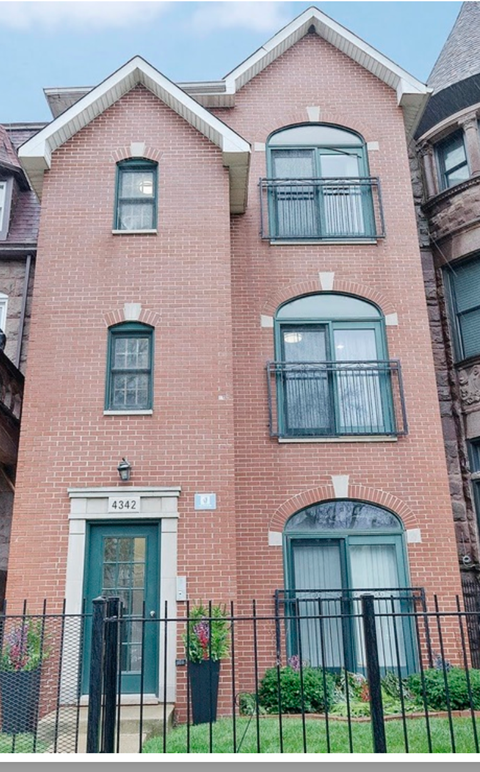 A red brick building with a green door and windows.