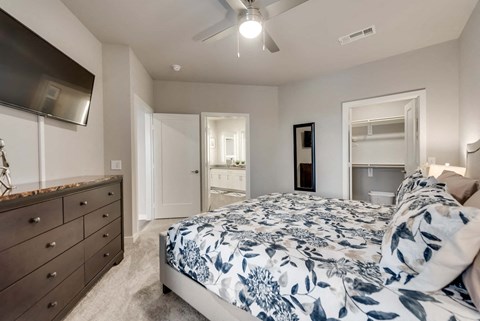 A bedroom with a bed, dresser, and ceiling fan.