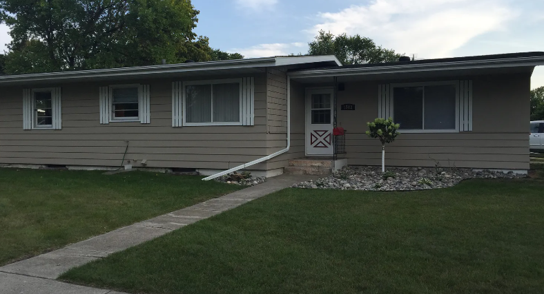 A beige house with a white door and windows.