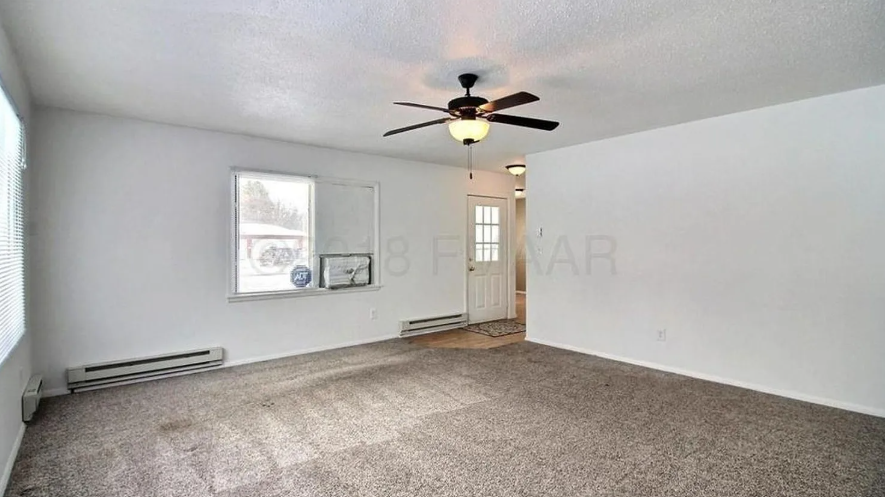 A spacious room with a ceiling fan and carpeted floor.