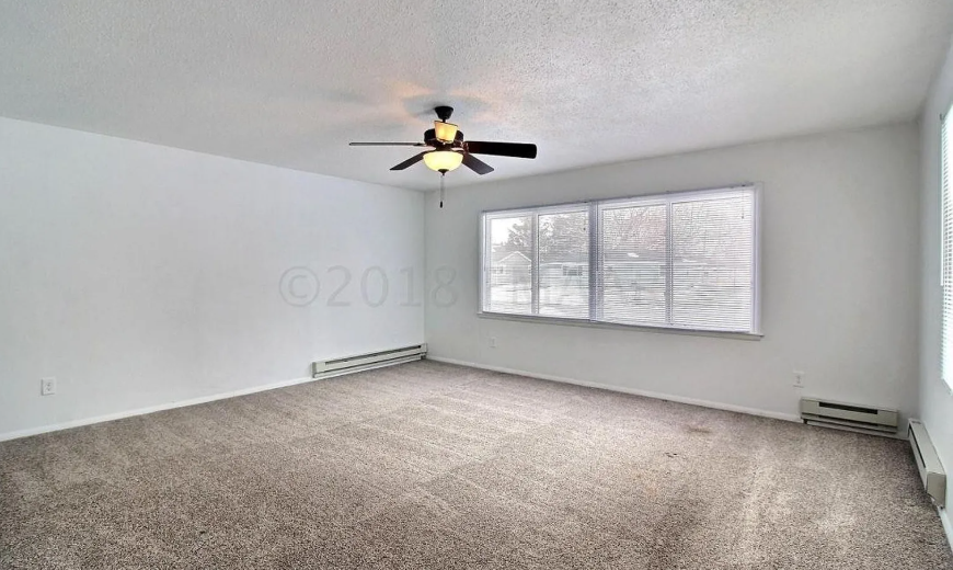 A room with a ceiling fan and a window with blinds.
