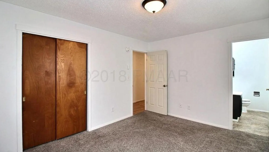 A room with a carpeted floor and two doors, one of which is closed.