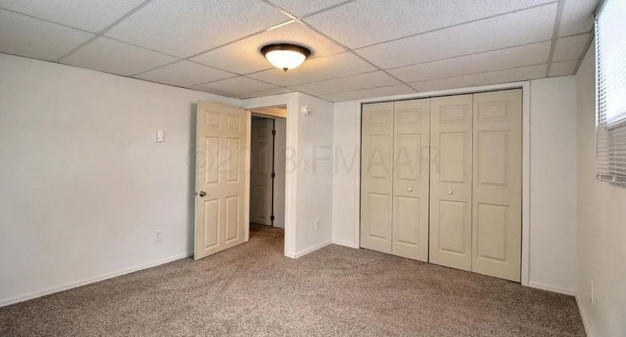 A room with a carpeted floor and a white ceiling with a light fixture.
