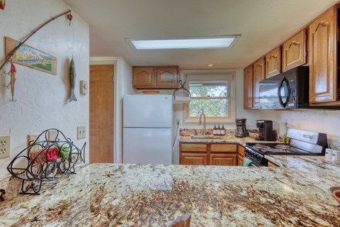 A kitchen with granite countertops and wooden cabinets.