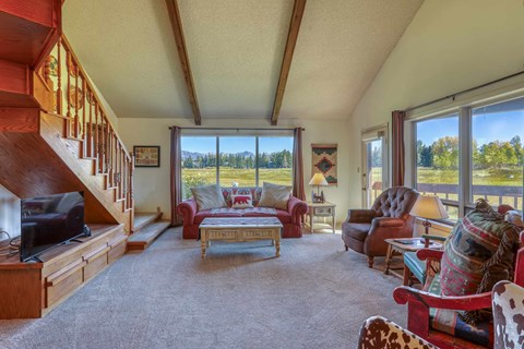 A living room with a staircase on the left and a couch with a blanket on it.