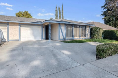 A house with a driveway and a tree in the background.