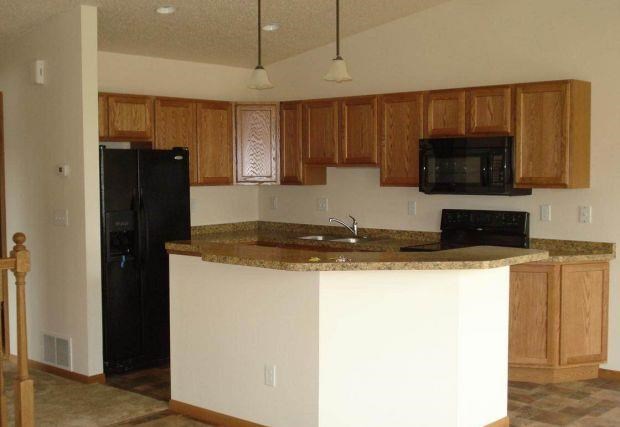 a kitchen with an island and a black refrigerator