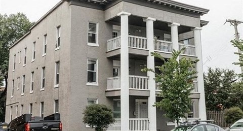 A grey building with white columns and balconies.