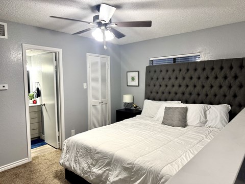 A bedroom with a large bed and a ceiling fan.