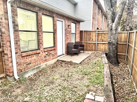 A small backyard with a tree and a wooden fence.