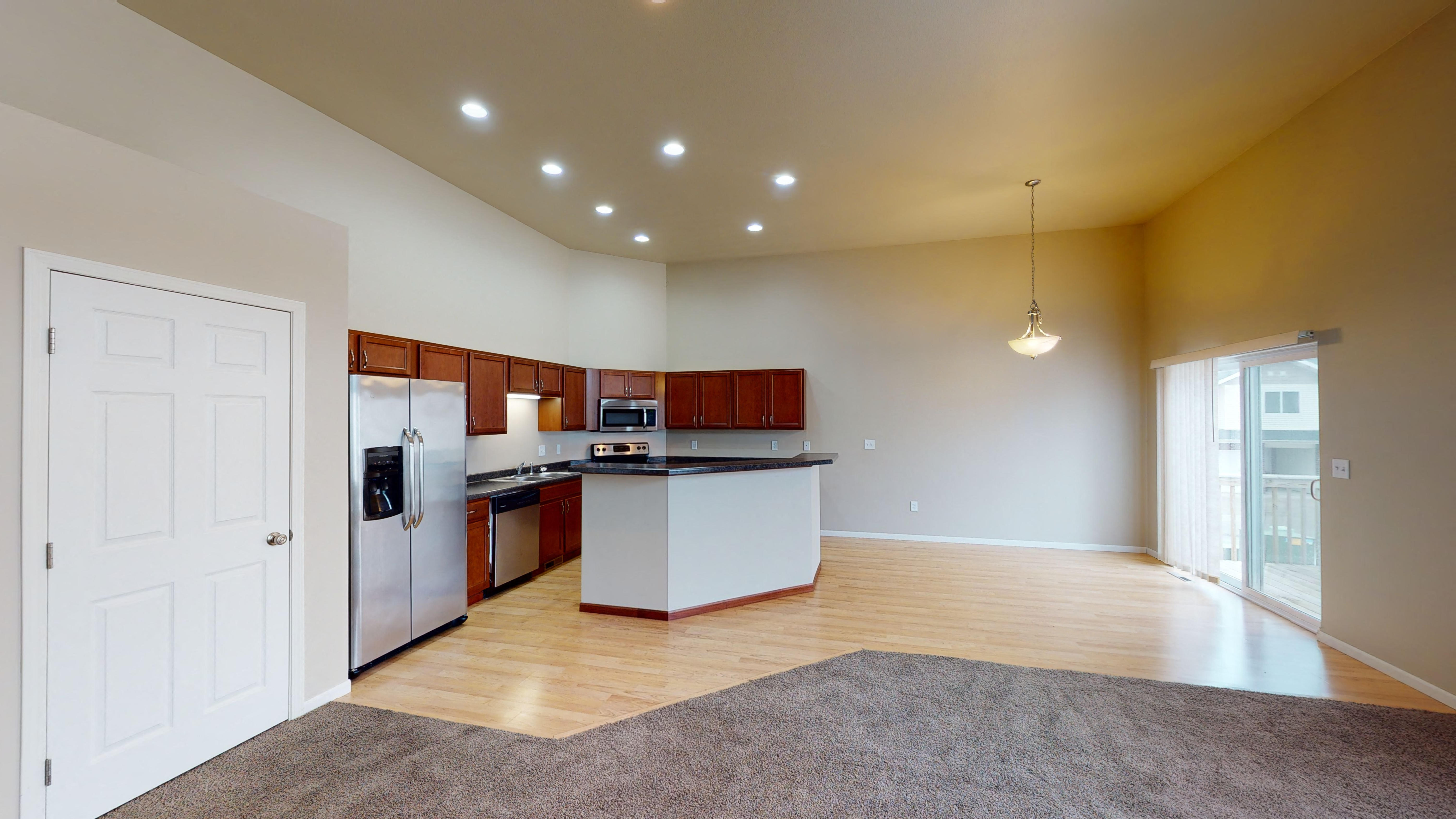 a kitchen with white appliances and wood flooring in a house