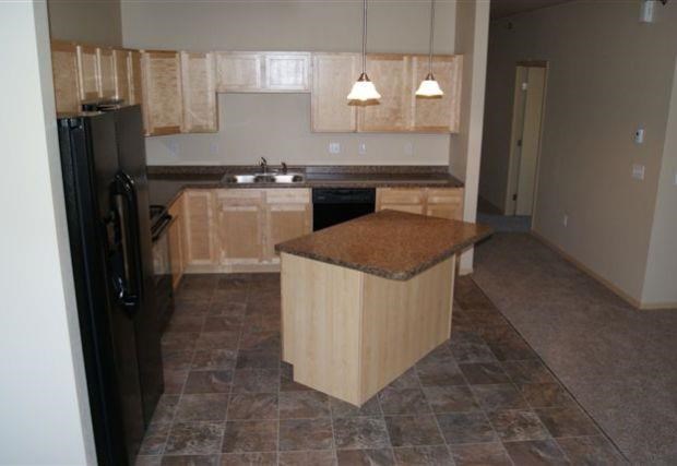 an empty kitchen with a counter top and a refrigerator