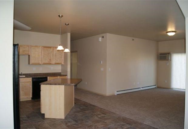 an empty living room with an empty kitchen with an island