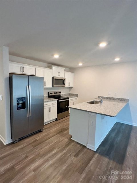 A kitchen with a refrigerator, microwave, and oven is for lease in 2024.