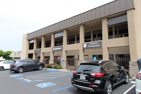 A black car is parked in a parking lot in front of a building with a sign that says Property Management.