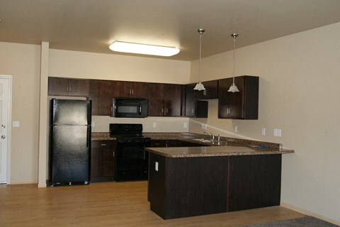 an empty kitchen with black appliances and a counter top