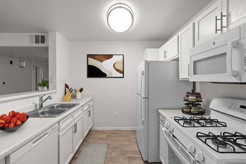 A kitchen with white cabinets and a white stove top oven.