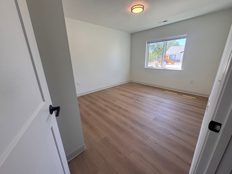 A room with a window and wooden flooring.