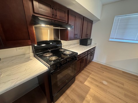 A kitchen with a black stove top oven and wooden cabinets.