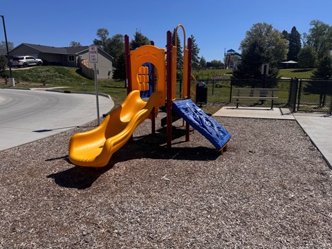 A playground with a yellow slide and a blue slide.