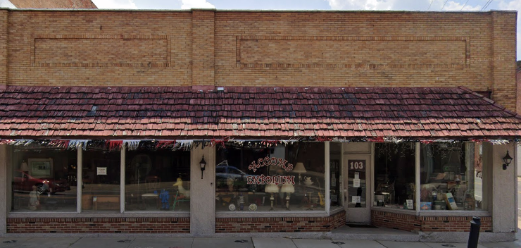 A red brick building with a red tile roof and a sign that reads 103.
