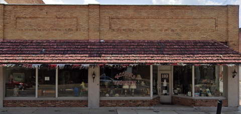 A red brick building with a red tile roof and a sign that reads 103.