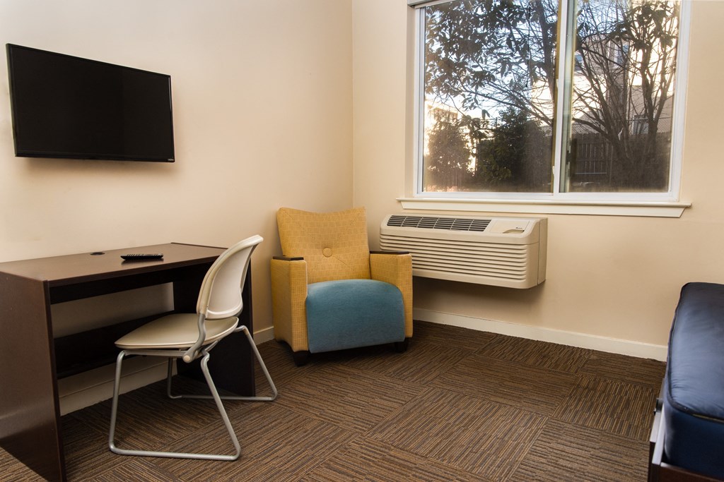 A room with a desk, chair, and window.