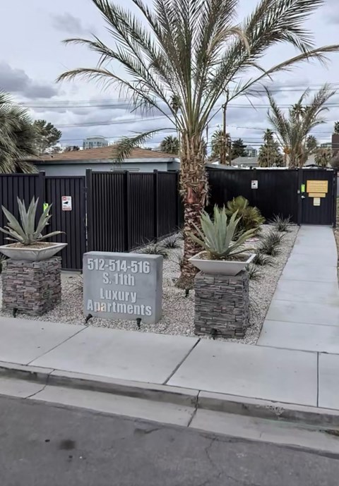 A sign for Luxury Apartments is displayed in front of a black fence.