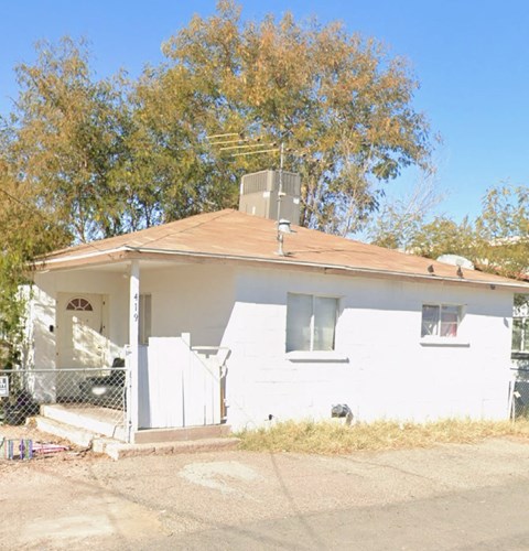 A white house with a brown roof and a fence in front.