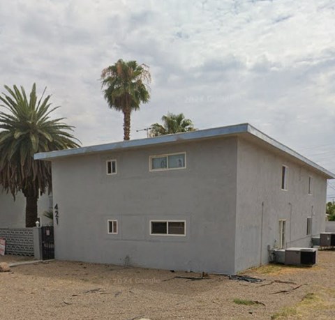 A house with a grey exterior and a palm tree in front.
