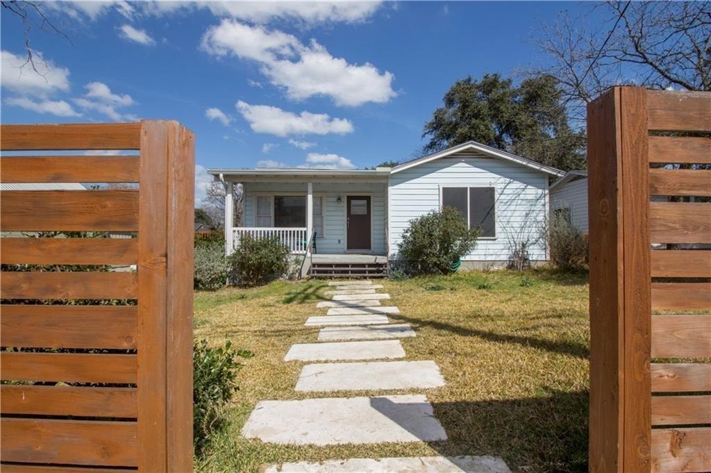 A small house with a wooden fence and a stone pathway leading to the front door.