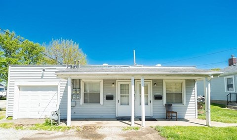 A small house with a porch and a garage.