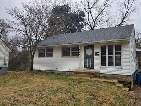 A small white house with a grey roof and a black door.