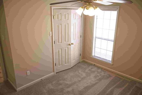 A room with a white door and a ceiling fan with lights.